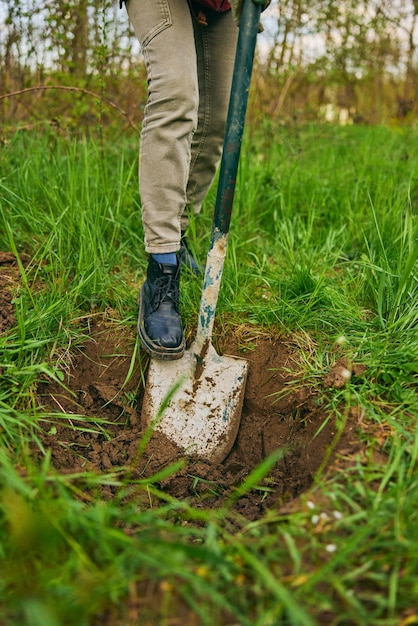 Female farmer digging ground in cloudy day woman working with shovel in field