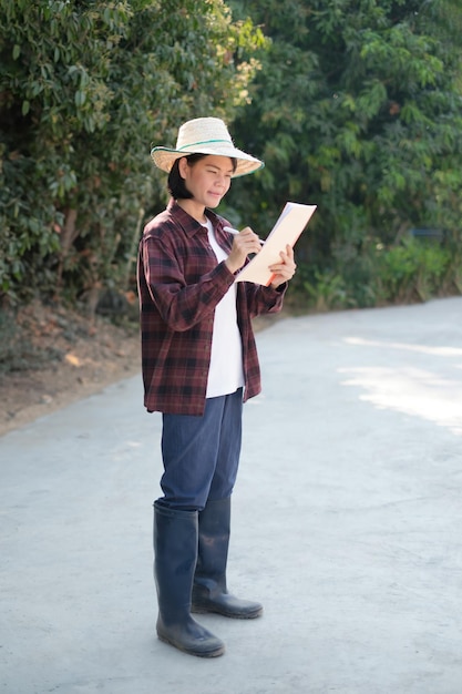 A female farmer wearing a red shirt is holding a noteboard