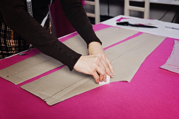 Female fashion designer tailor making sewing patterns at workplace in sewing studio seamstress