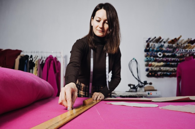 Female fashion designer tailor making sewing patterns at workplace in sewing studio seamstress