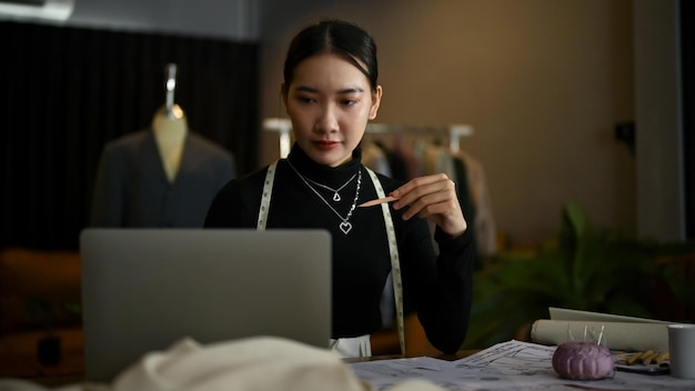 A female fashion designer using laptop and working on her new collection in her studio