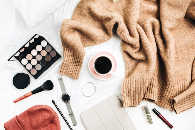 Female fashion look with stylish clothes and accessories. Lifestyle flat lay composition with sweater, cosmetics and coffee.