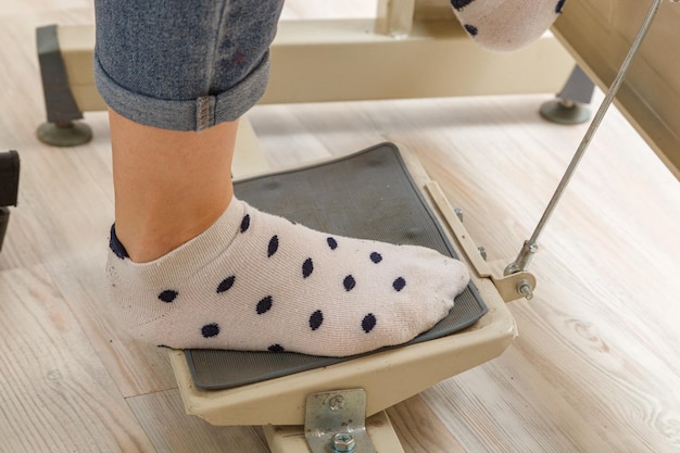 Female feet on the pedal of a sewing machine motor