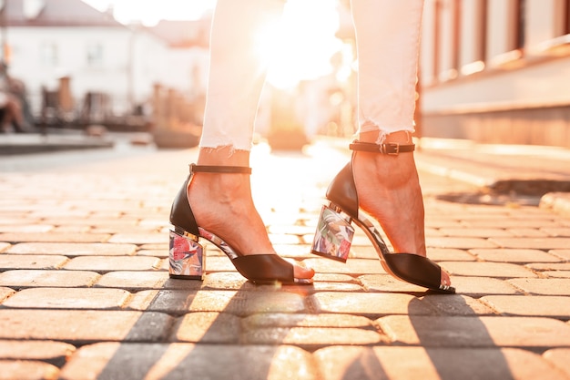 Female feet with fashionable black shoes in the city at sunset