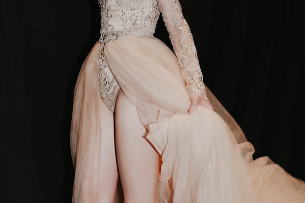 Female figure in a lush evening beige dress on a black background