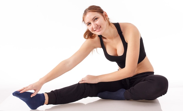 Female fitness model excercising in studio with dunbell weights and doing a floor routine of stretches and lifts on a matt