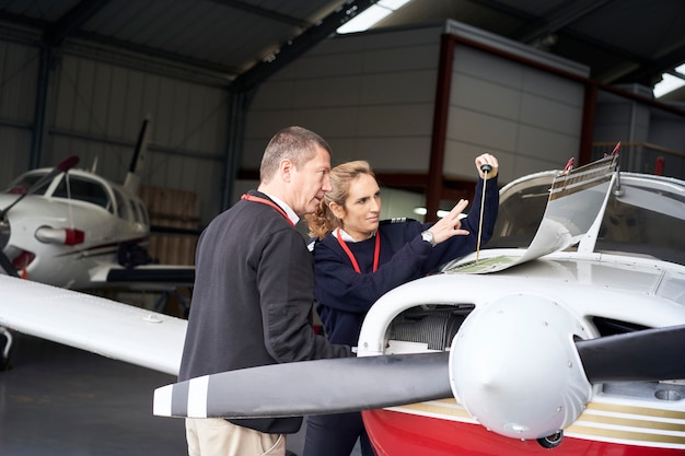 Female flight instructor teaching her student how to do the maintenance of the plane