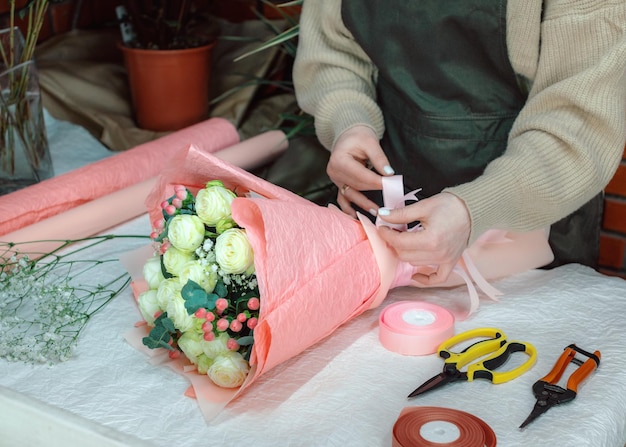 Female florist creating beautiful bouquet at workplace in flower shop close up floristics workshop