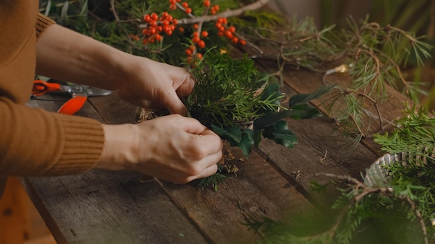 Female florist creating Christmas wreath in flower shop