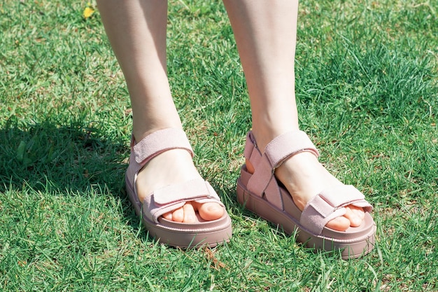 Female foot in summer sandals against background of green grass