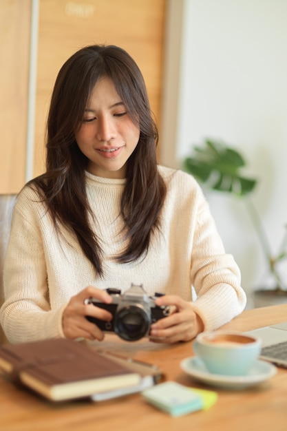 Female freelance photographer looking and checking her photograph on her camera at cafe