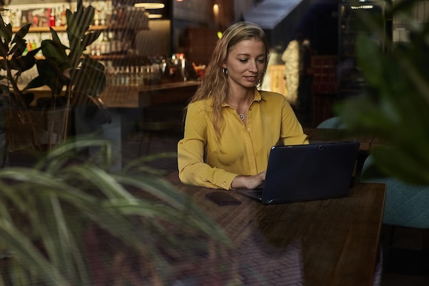 Female freelancer sitting at table shot through window glass outside of cafe