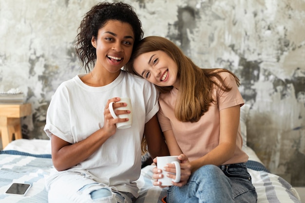 Female friends embraced with coffee mugs at home