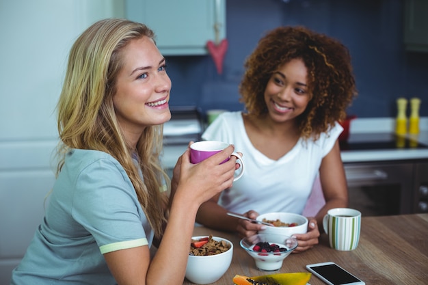 Female friends having breakfast at table in kitchen