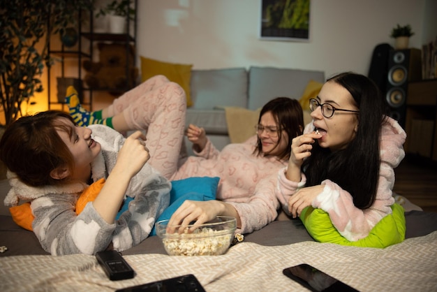 Female friends having fun together at home party yonung woman in funny onesies at pajama party