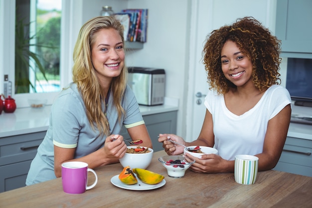 Female friends smiling while having breakfast in kitchen