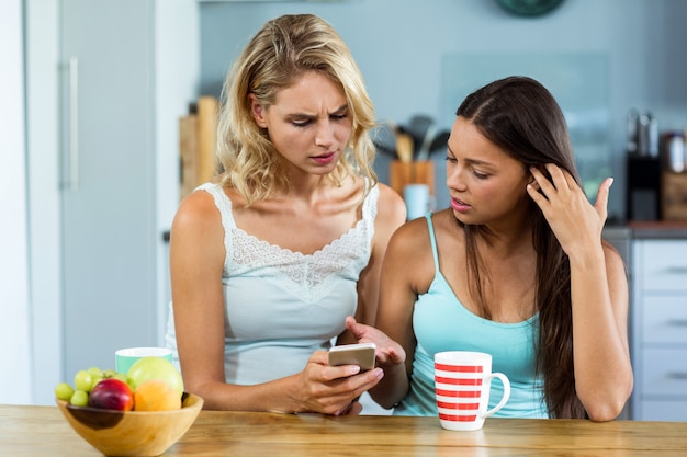 Female friends using mobile phone at home