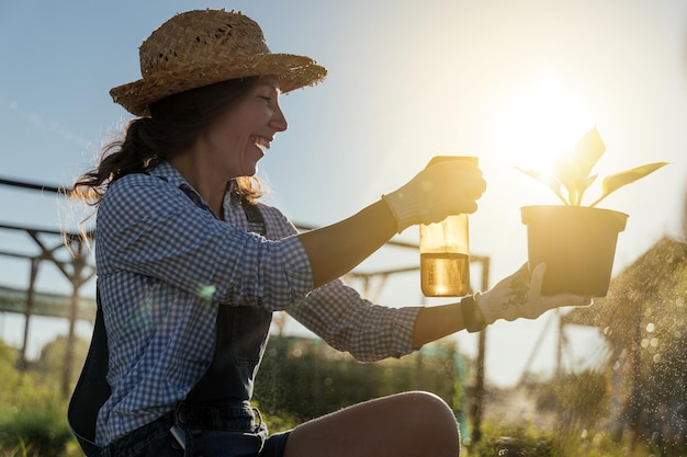 A female gardener sprays a plant with a water sprayer in the garden