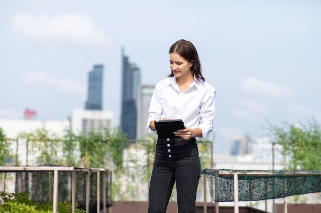 of female gardener working in rooftop vegetable garden at the modern building