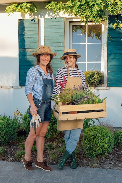 Female gardeners with a box of plants in hands in the garden