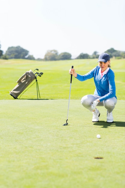 Female golfer watching her ball on putting green 