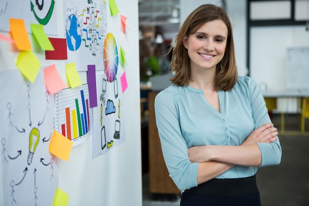 Female graphic designer standing with hands crossed in creative office