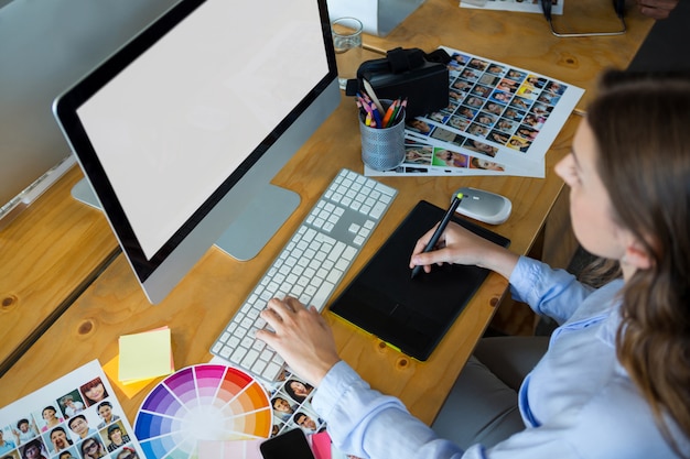 Female graphic designer using graphics tablet at desk