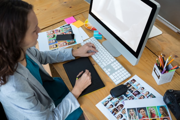 Female graphic designer using graphics tablet at desk