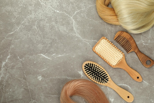 Female hair and hairbrushes on gray textured background