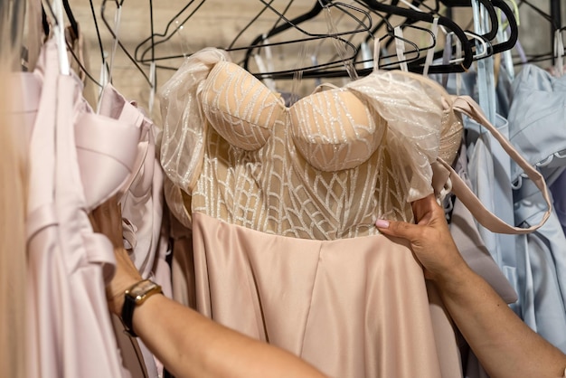 Female hand choosing the best evening coctail dress for party in clothes store