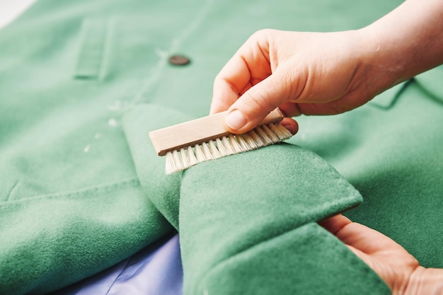 Female hand cleans coat fabric with a small brush Worker performs dry laundry hand cleaning garments Clothes cleaning and care service