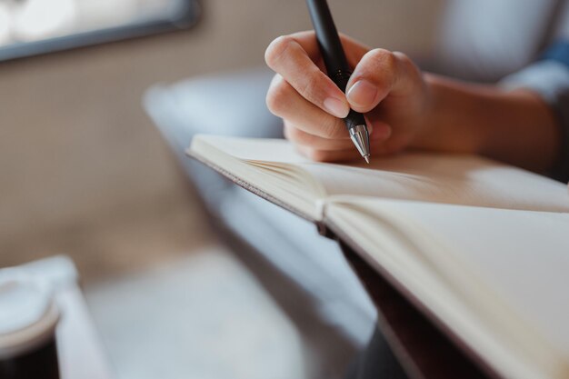 Female hand closeup writes with a pen in a blank notebookshe writing a daily lifetimeBusiness woman workerwriter personal blog Concepts