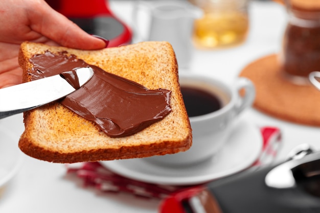 Female hand cooking toast with chocolate paste