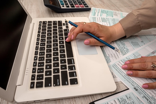 Female hand  filling US tax form 1040 with help calculator and laptop in the office