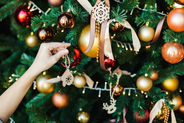 Female hand hangs on the Christmas tree wooden toy in the form of mittens. 