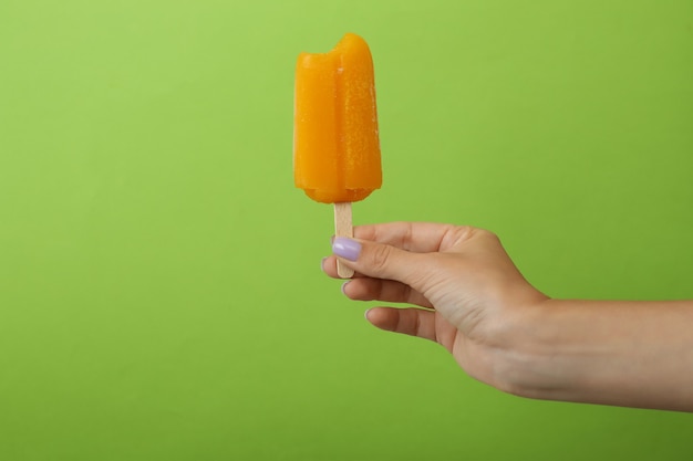 Female hand hold ice cream stick on green