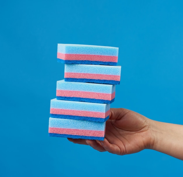 Female hand holding blue stack of kitchen sponges