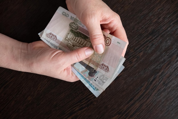 Female hand holding a bundle of banknotes Russian rubles closeup on black background poverty