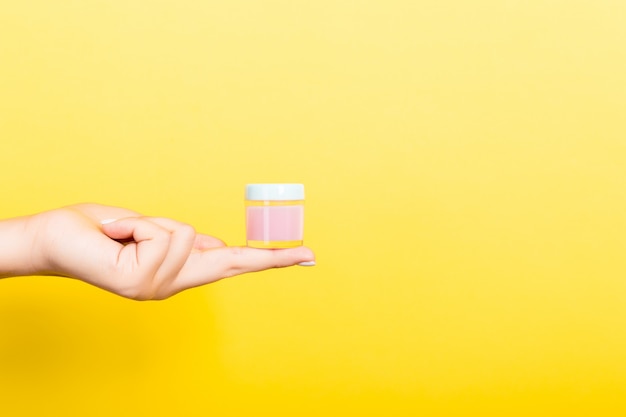 Female hand holding cream bottle of lotion