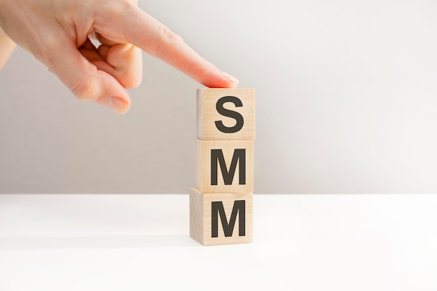 Female hand holding a cube, SMM letters on wooden cubes, business concept