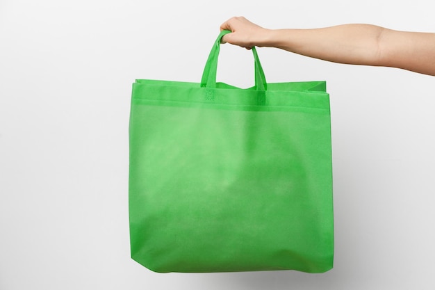 Female hand holding eco or reusable shopping bag against white background