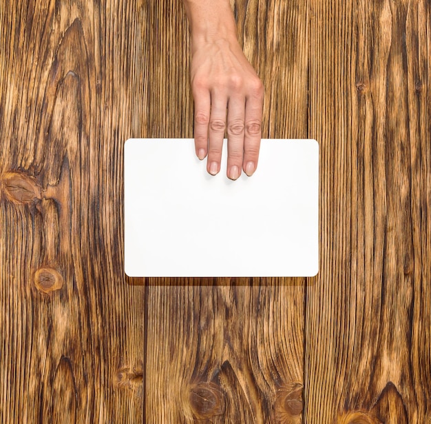 Female hand holding empty white sheets on wooden background