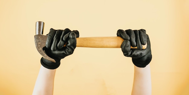 Female hand holding hammer on yellow background panoramic mockup with copy space new house work at home woman working DIY