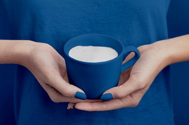 Female hand holding milk cup on color of the year