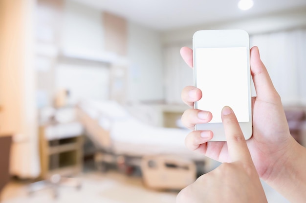 Female hand holding mobile smart phone with blurred hospital background