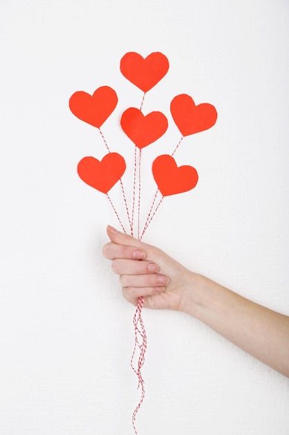 Female hand holding paper balloons, on white wall background