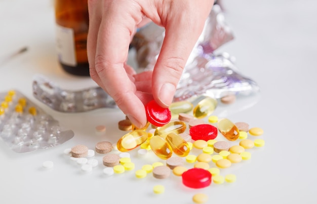 Female hand holding pills in hand. Woman holding pills in hand on background of colored tablets and capsules