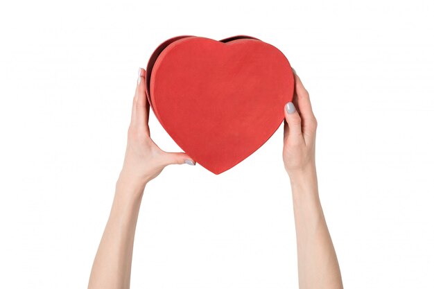 Female hand holding a red box in the shape of a heart. Isolate