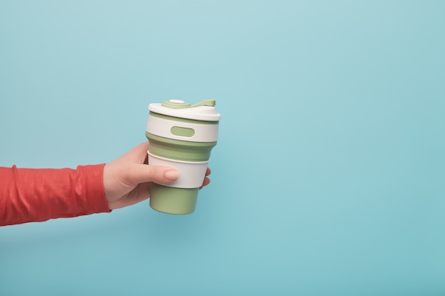 Photo female hand holding a silicone reusable cup.