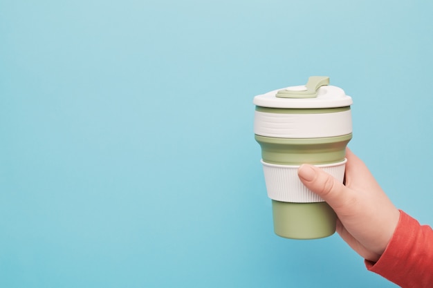 Photo female hand holding a silicone reusable cup